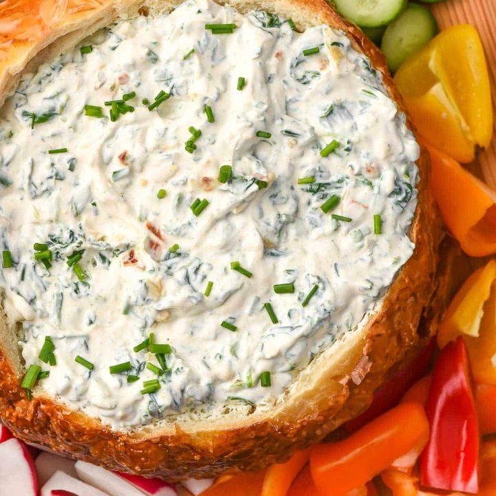 Knorr Spinach Dip recipe shown in a bread bowl surrounded by cut vegetables.