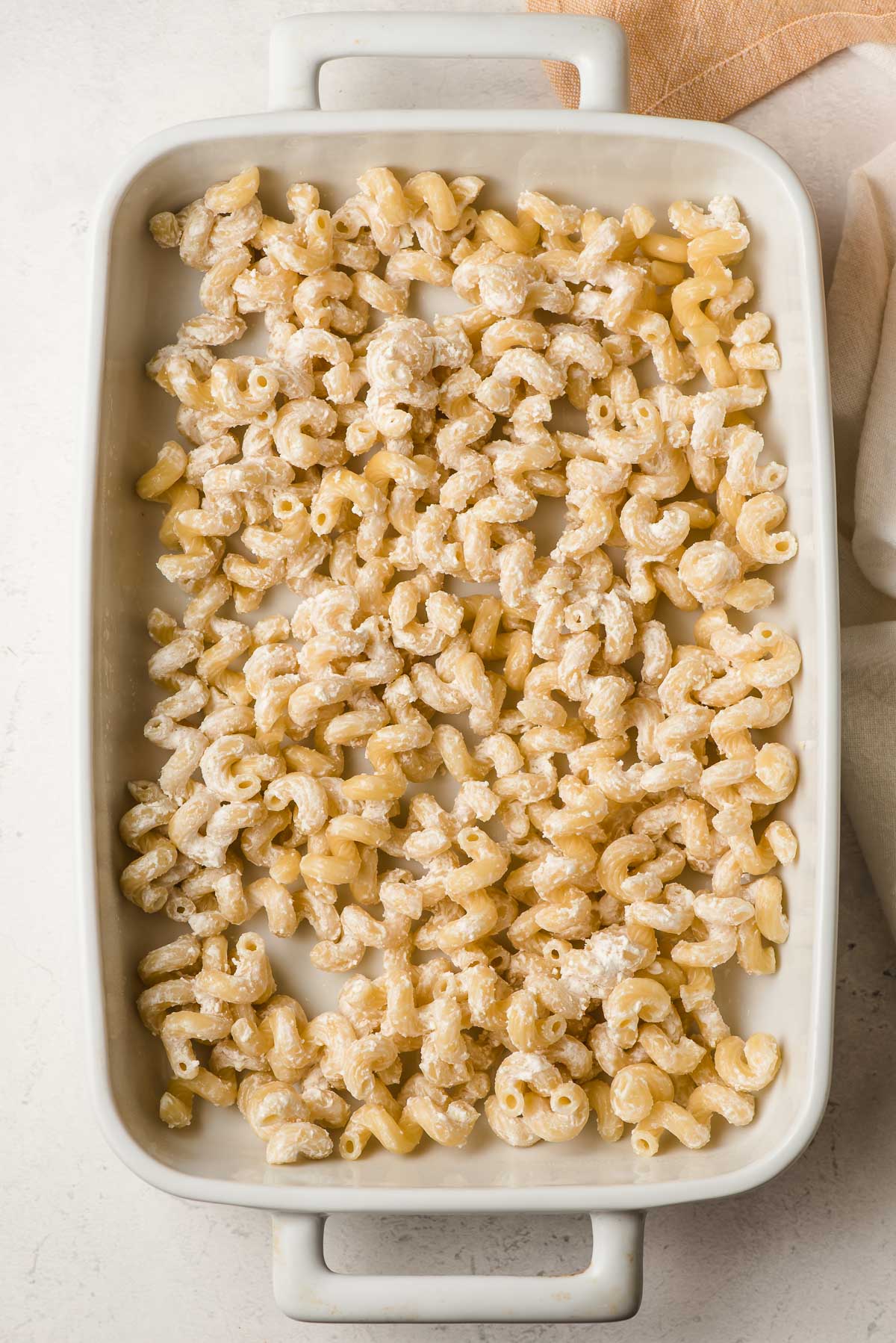 Cavatappi noodles tossed with sour cream in a casserole dish.
