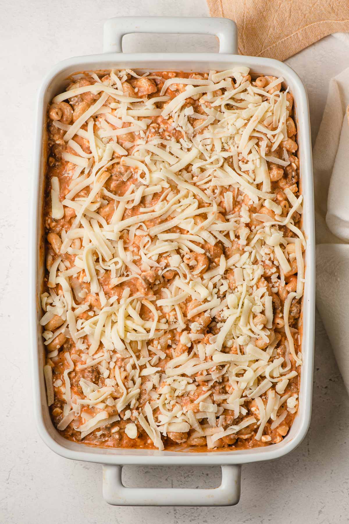 Ground beef pasta casserole covered with mozzarella cheese, before baking.