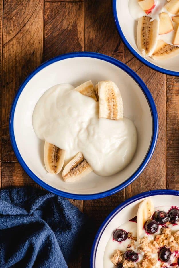 Scoop of yogurt on top of a sliced banana in a bowl.