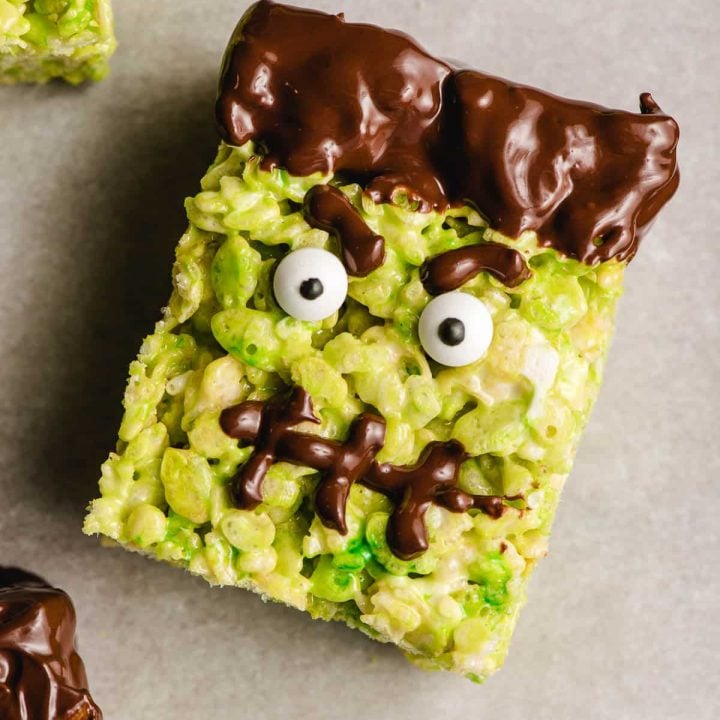 Frankenstein rice krispie treat with angry eyebrows, googly eyes, and a chocolate stitched mouth.
