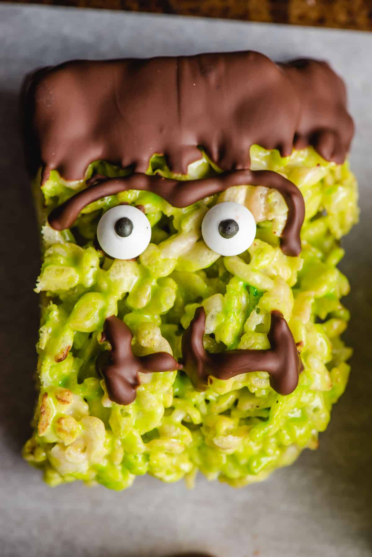A Frankenstein rice krispie treat with googly eyes, a unibrow, chocolate hair, and stitches for a mouth.