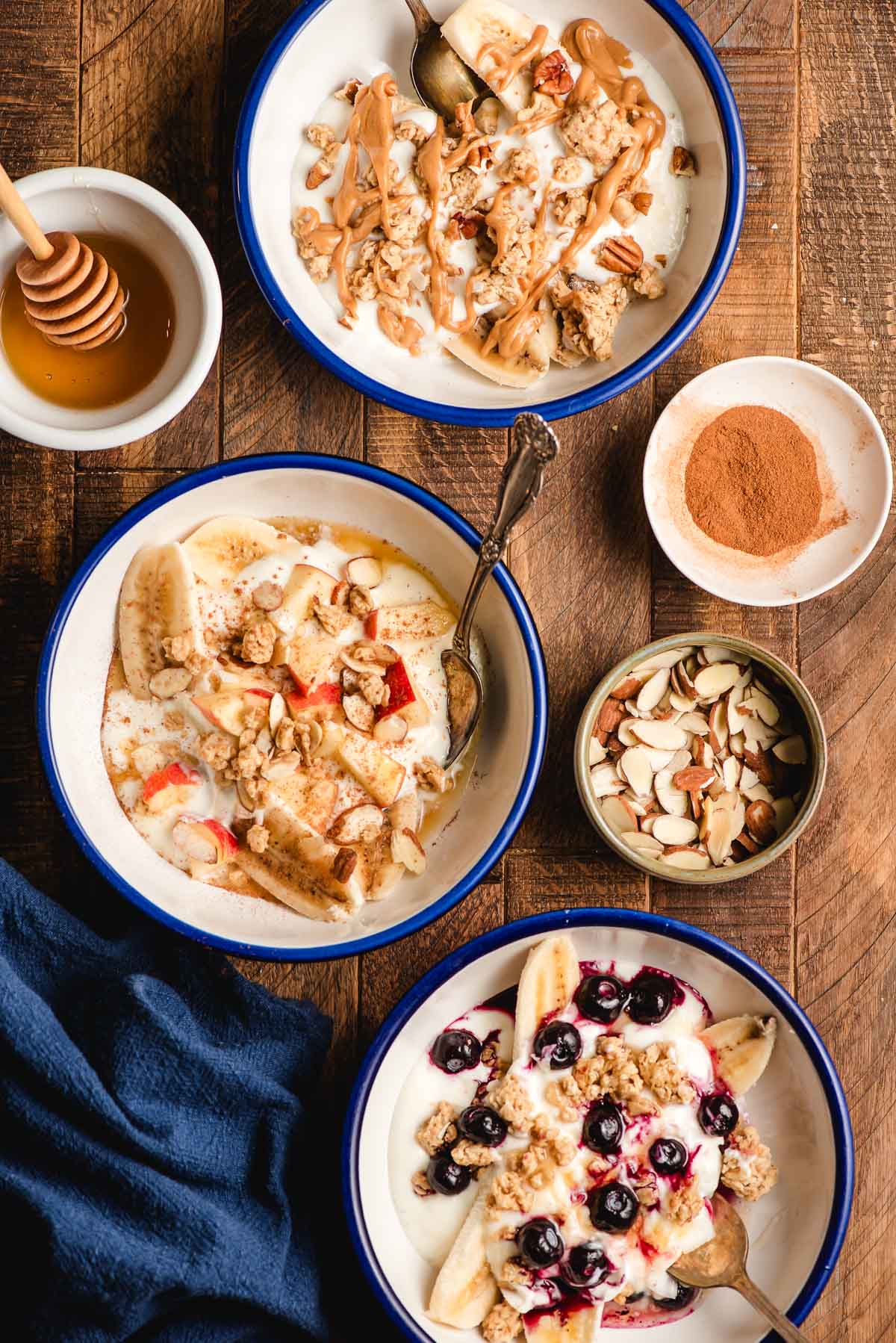Three bowls of different breakfast banana splits with yogurt and toppings.
