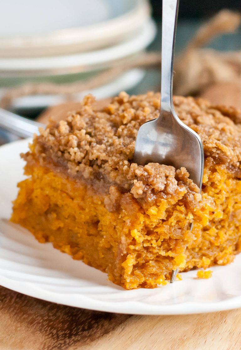 Fork taking a bite out of a slice of pumpkin crumb cake on a plate.
