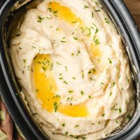 Crock Pot Mashed Potatoes with sour cream, melted butter, and chives on top.