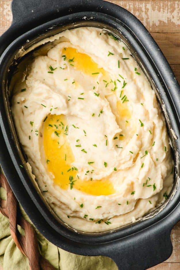 Crock Pot Mashed Potatoes with sour cream, melted butter, and chives on top.