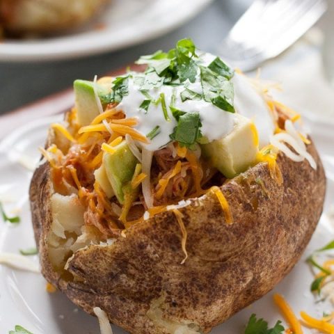 These Chicken Enchilada Baked Potatoes are loaded with saucy shredded chicken, cheese, sour cream, and avocado! A perfect weeknight meal.
