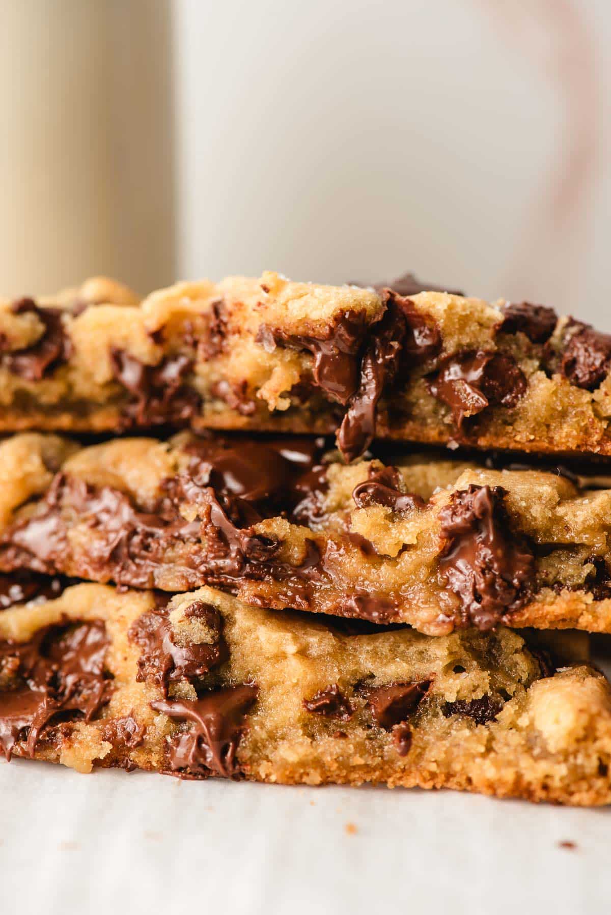 Stack of chocolate chip cookies broken in half to reveal the melty chocolate chips.