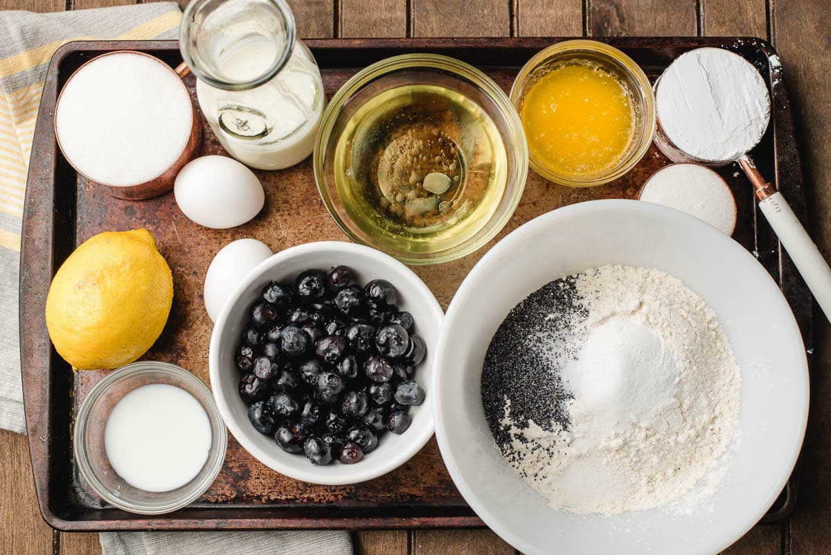 Bowls with dry ingredients, blueberries, buttermilk, eggs, powdered sugar, oil, and lemons.
