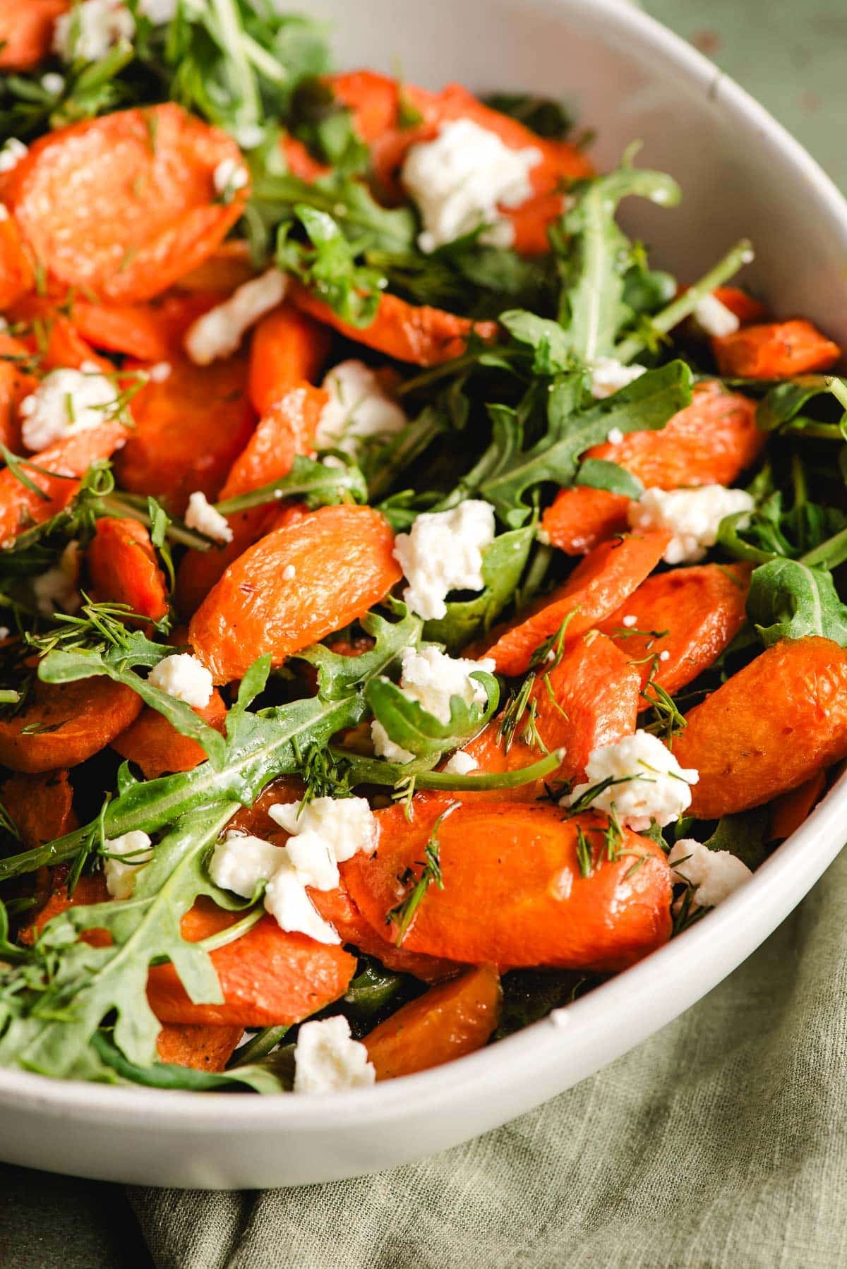 Roasted carrot salad with arugula and feta cheese in a white bowl.