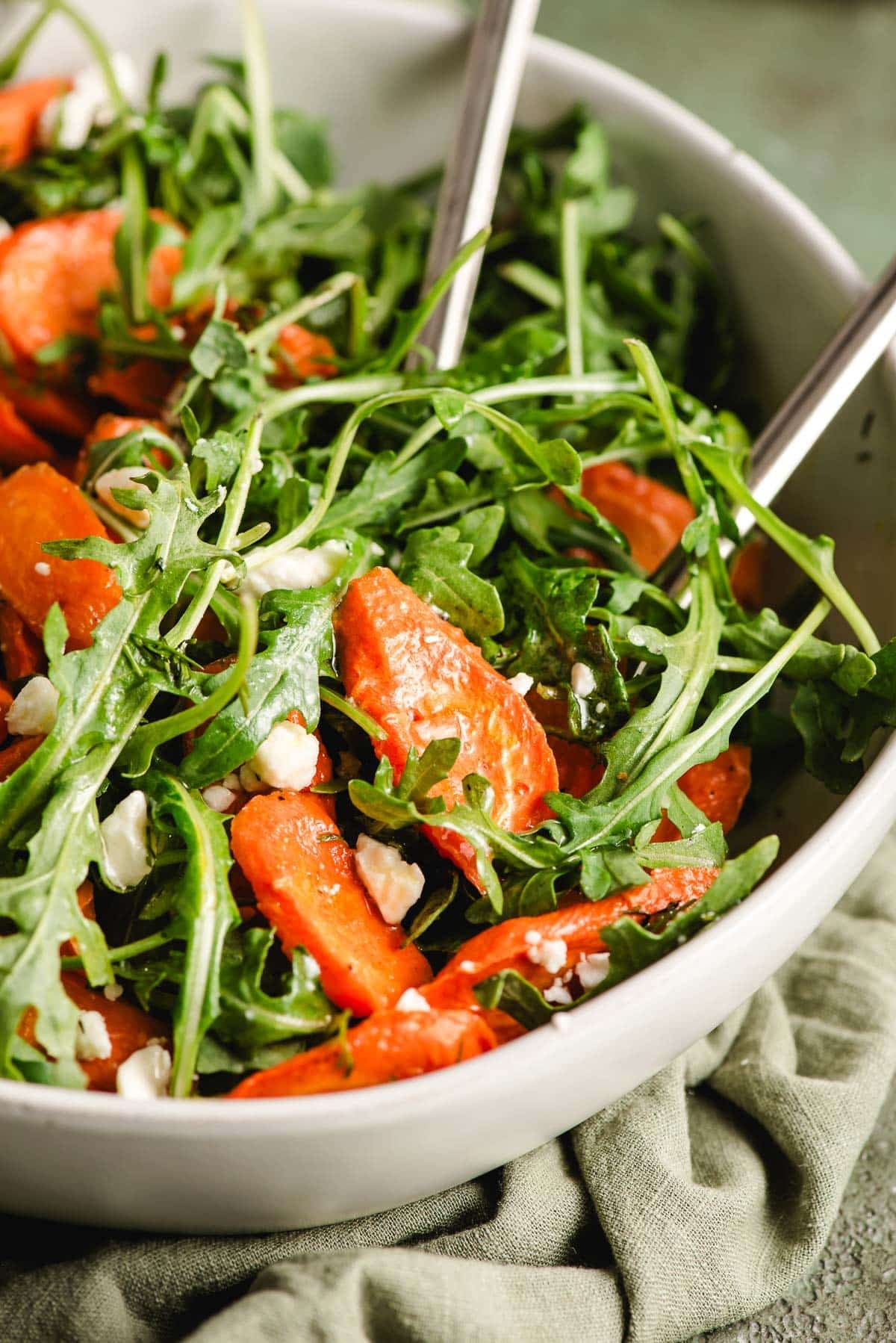 Salad forks scooping up roasted carrot salad out of a bowl.