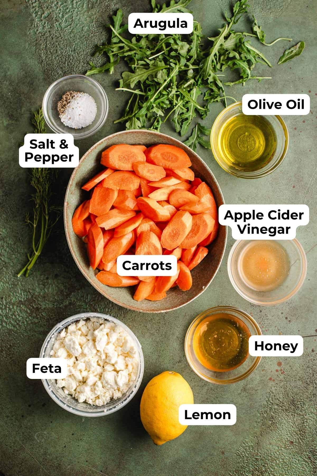 Arugula, salt and pepper, olive oil, bowl of carrots, bowl of crumbled feta, whole lemon, apple cider vinegar, and honey.