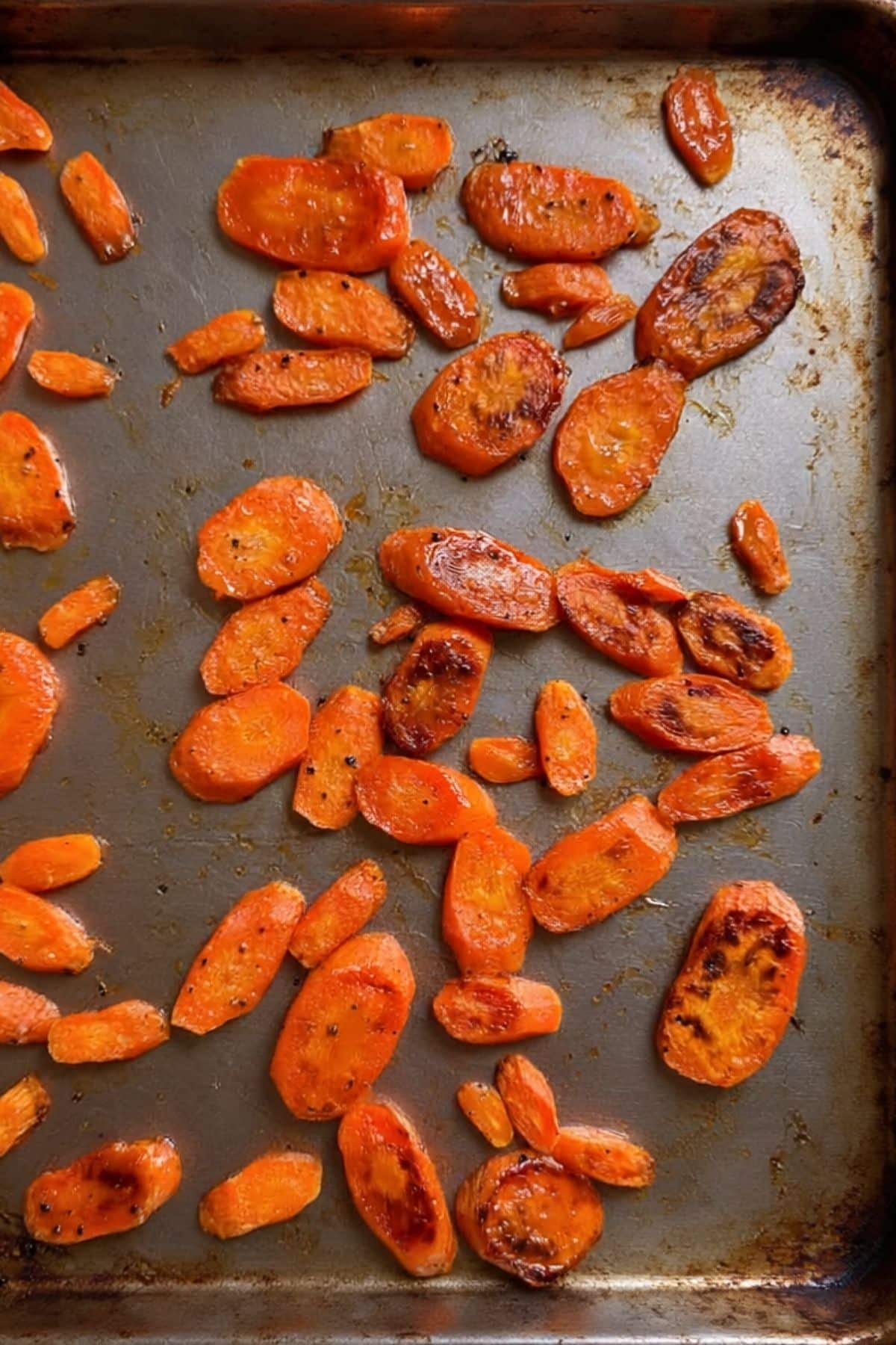 Roasted sliced carrots on a sheet pan.