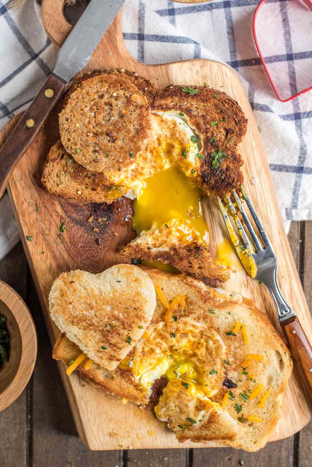 A fork breaks open the yolks of eggs in a basket on a board