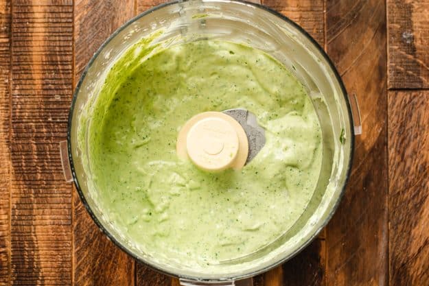 Creamy avocado dressing shown in a food processor.