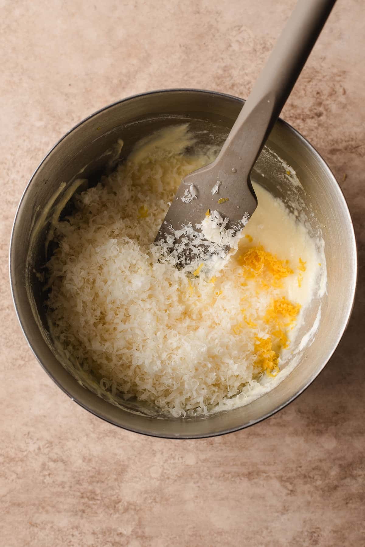Ricotta, Parmesan, lemon juice and zest, and an egg yolk in a metal mixing bowl.