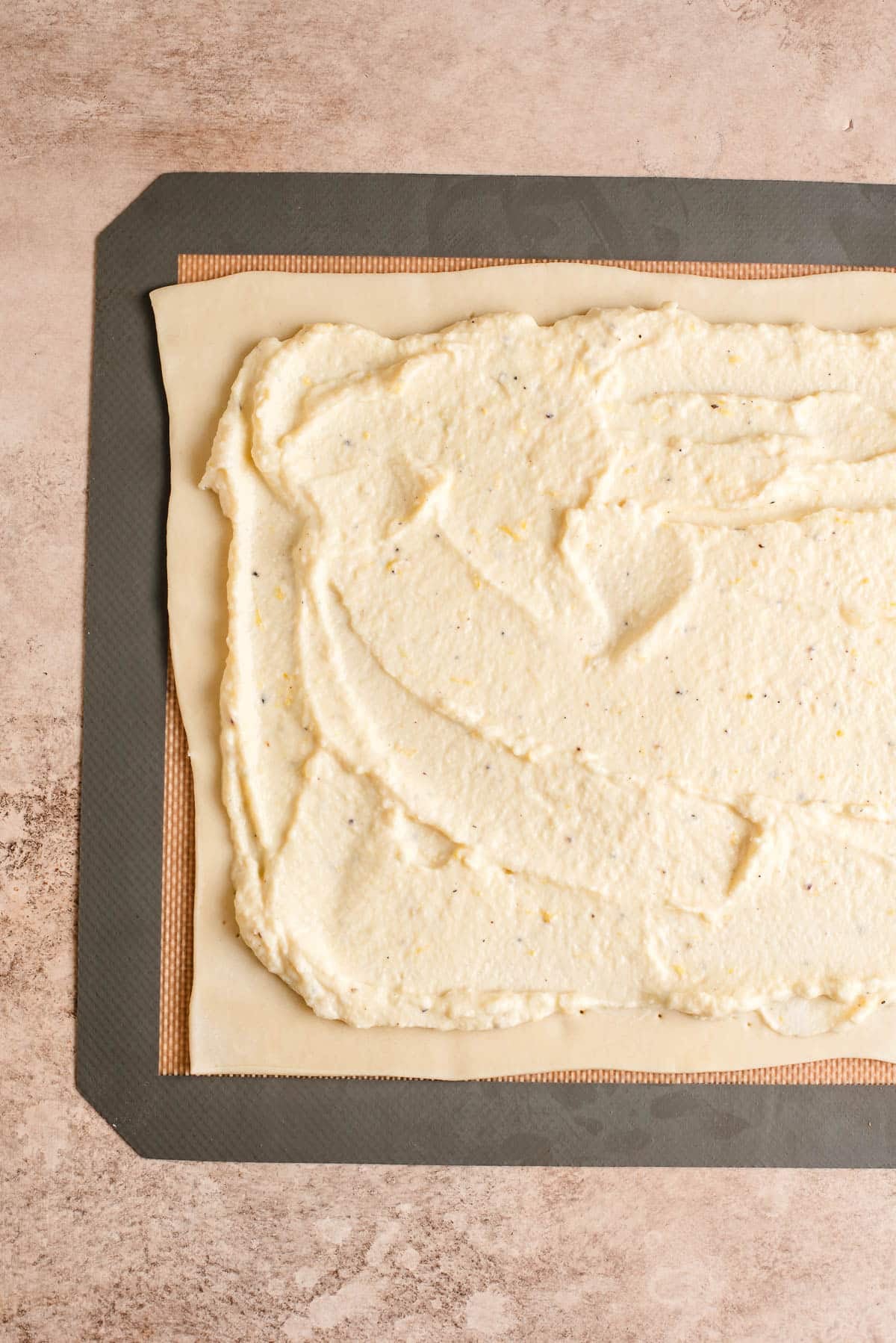 Ricotta and parmesan cheese blend spread over a puff pastry sheet.