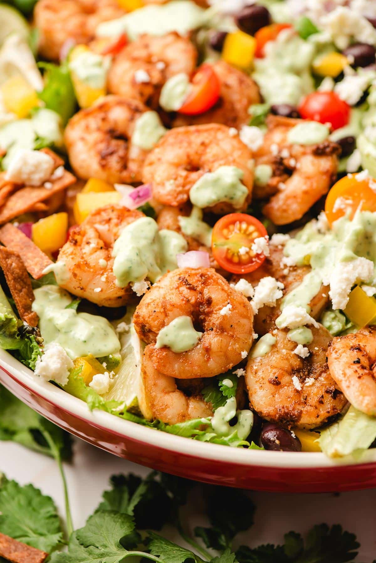 Shrimp salad with taco fixings and an avocado dressing on top.