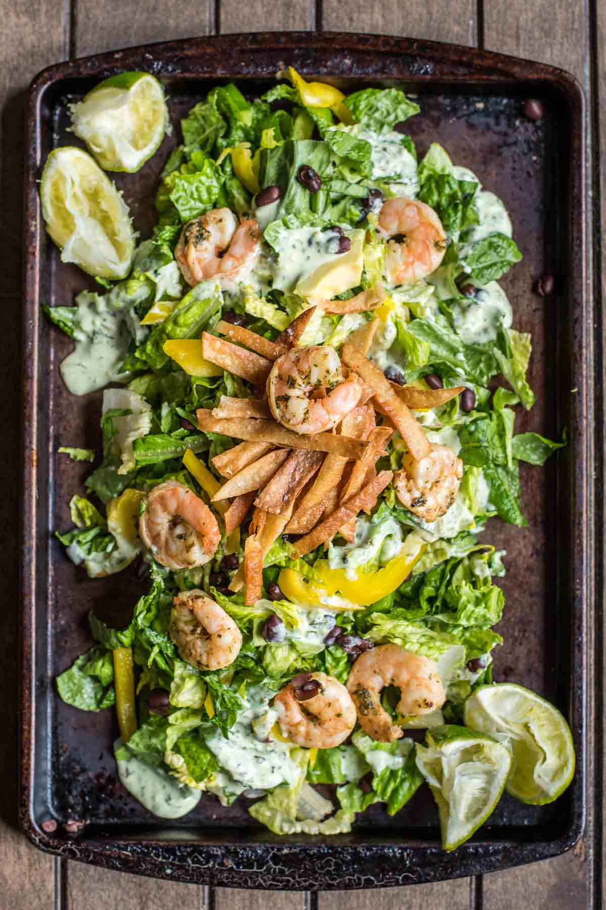 This Shrimp Taco Salad is loaded with spicy shrimp, crispy tortilla strips, bell pepper, and a creamy avocado dressing.
