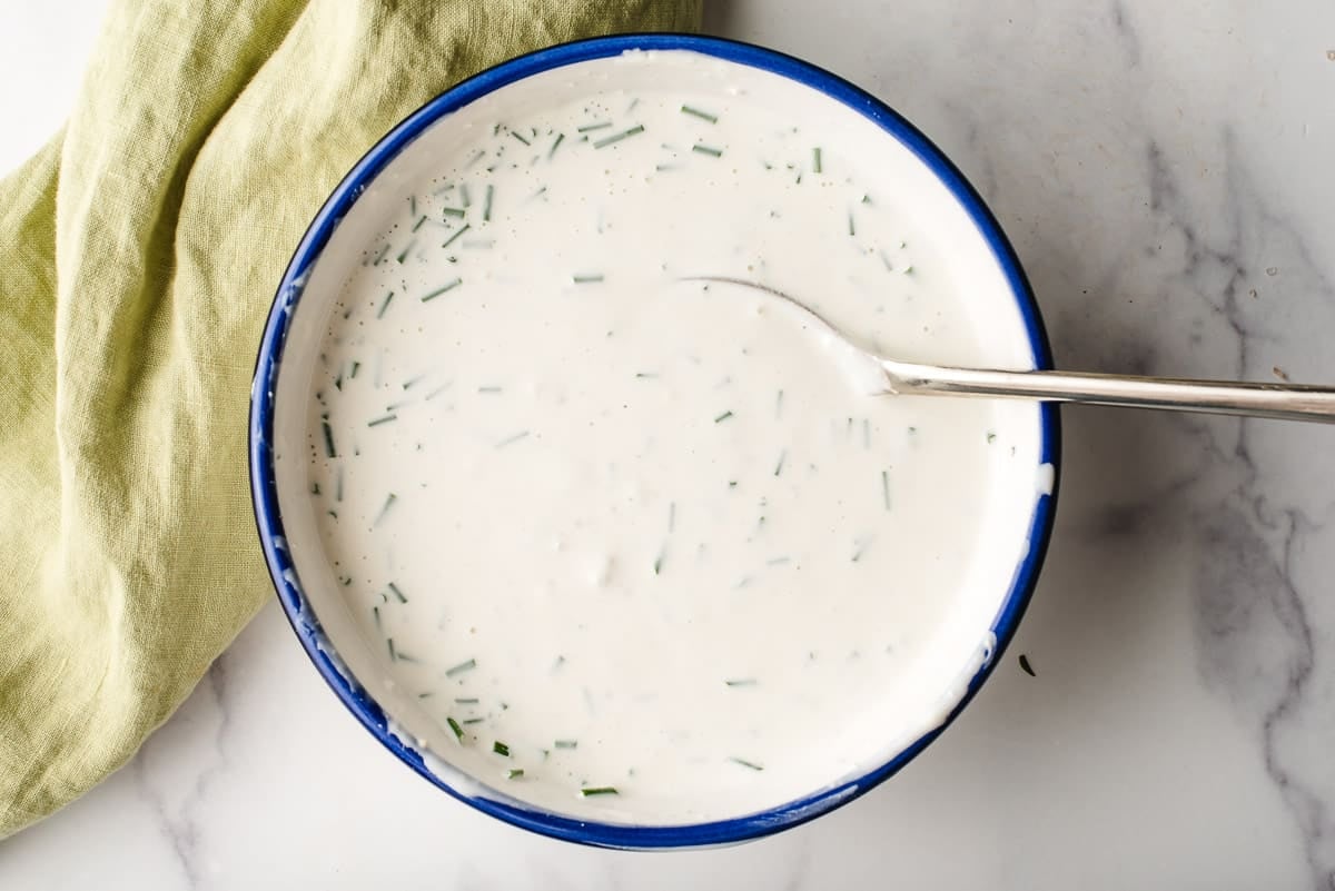 Homemade blue cheese dressing in a blue rimmed bowl.