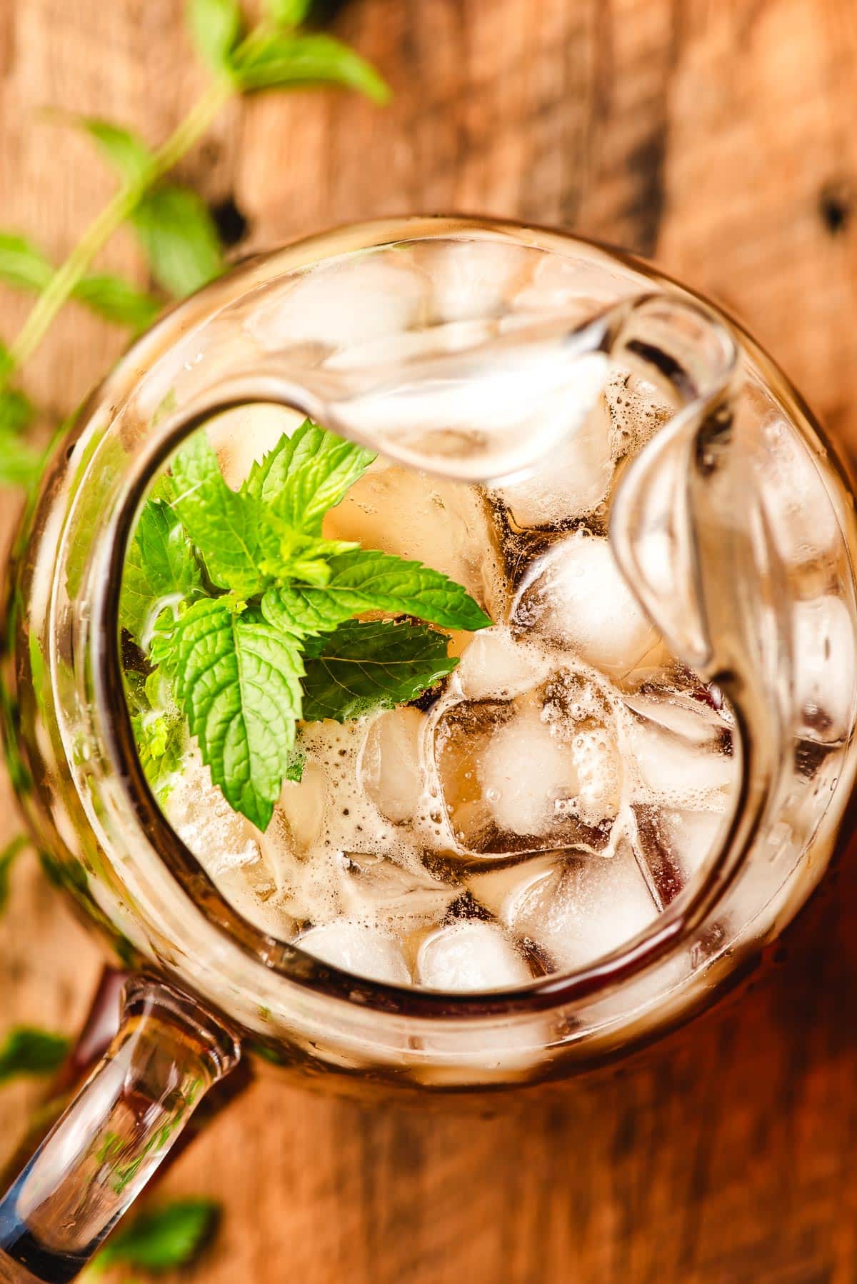 Pitcher of iced spearmint tea, garnished mint fresh mint leaves.