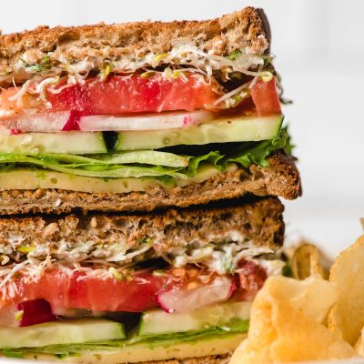 The best veggie sandwich sliced and stacked on a white plate.