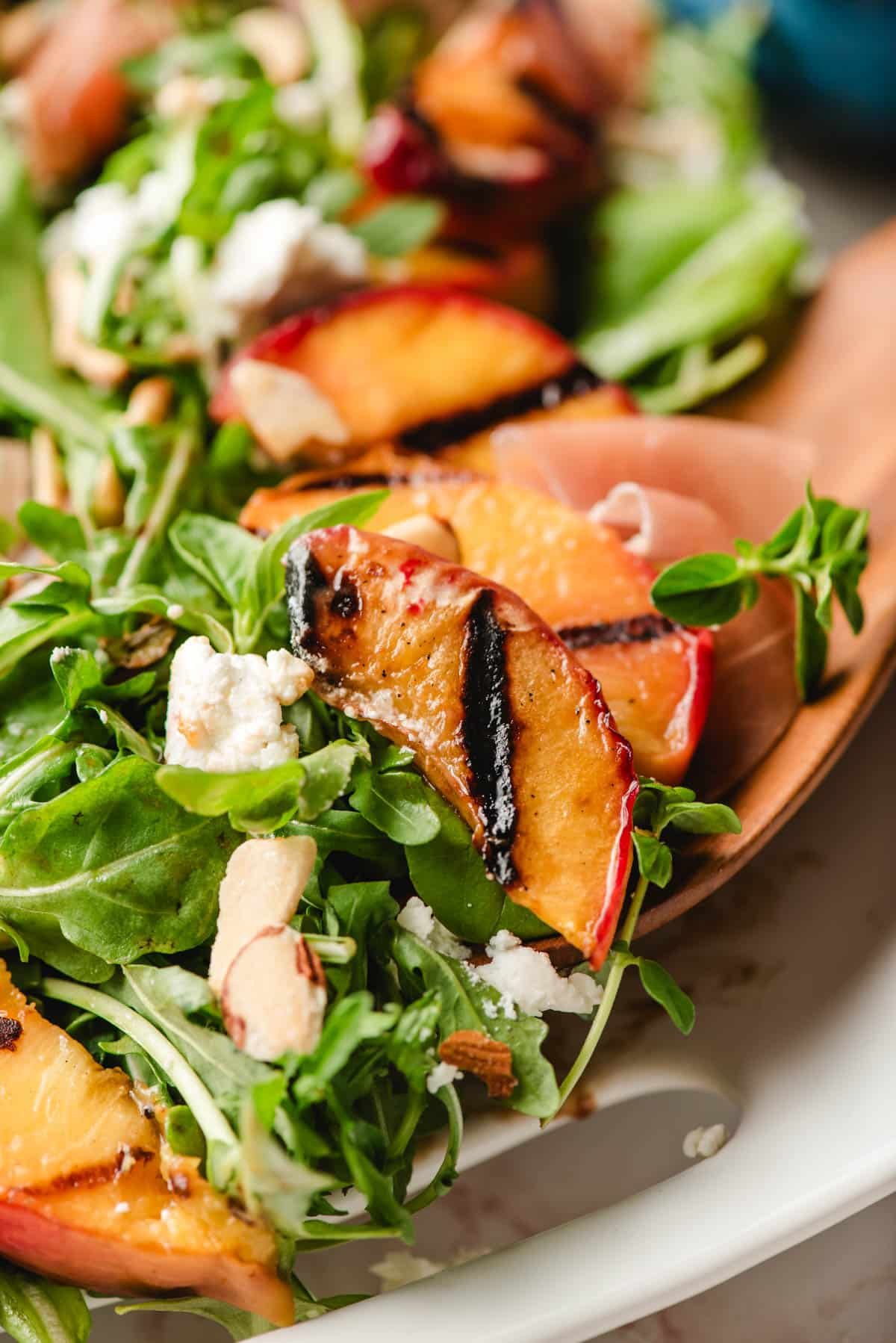 Scoop of grilled peach salad with goat cheese and almonds.