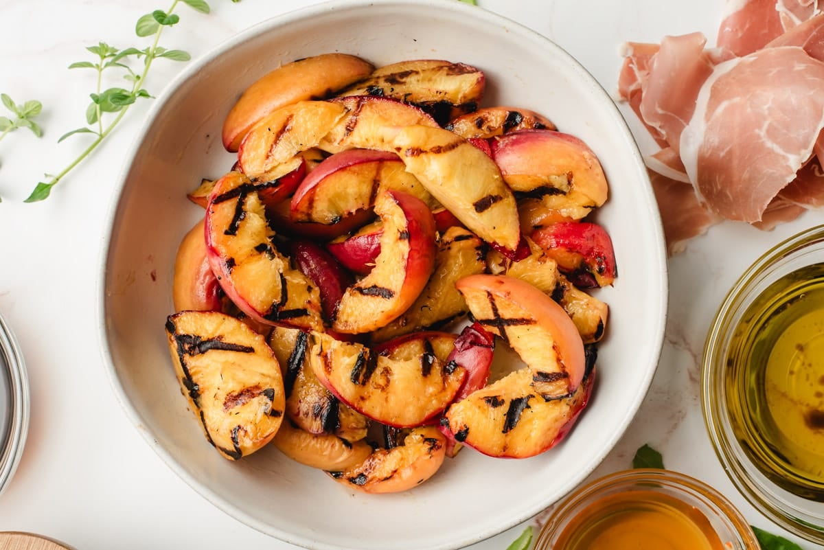 Grilled peaches in a white bowl.