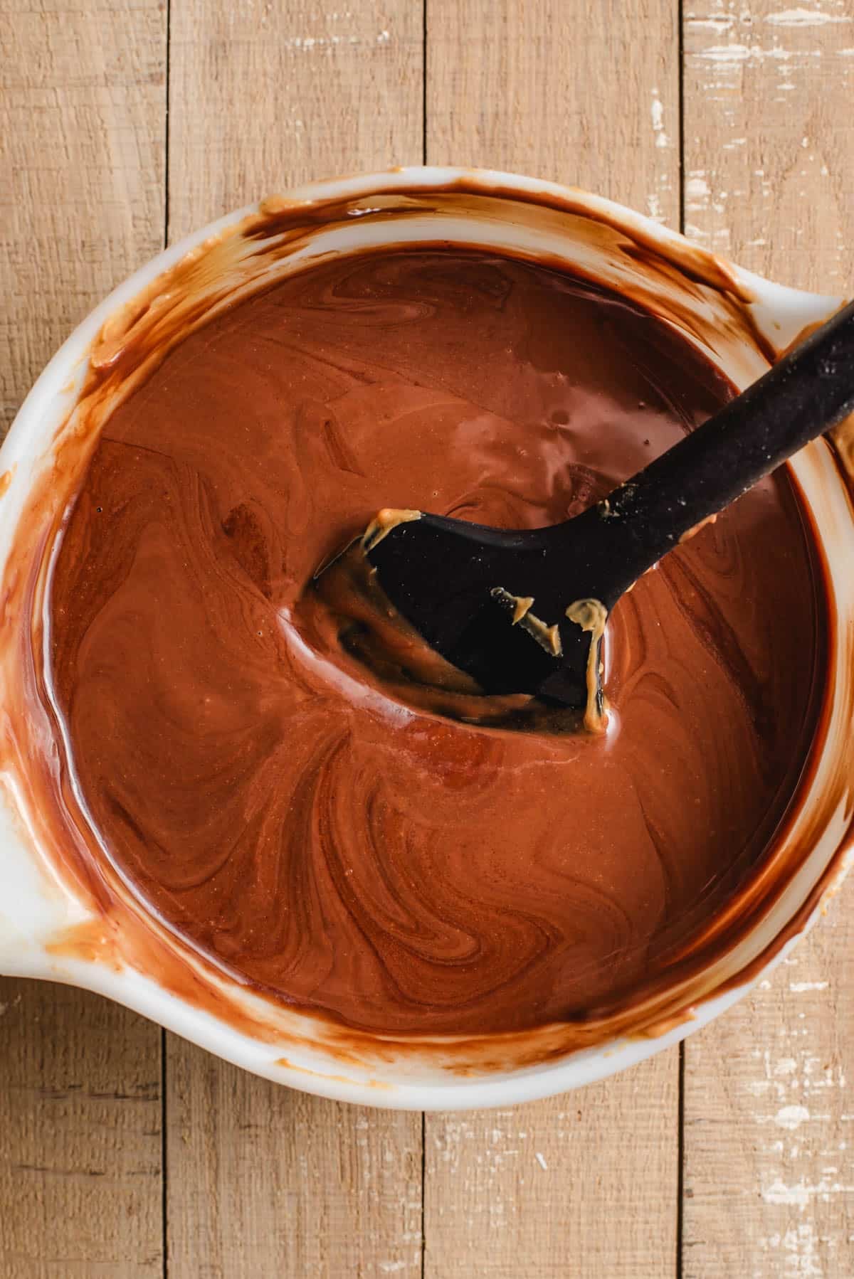 Chocolate chips, peanut butter, and butter melted together in a white bowl.