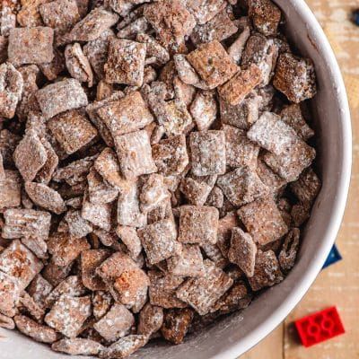 Chocolate peanut butter puppy chow in a bowl, surrounded by legos.
