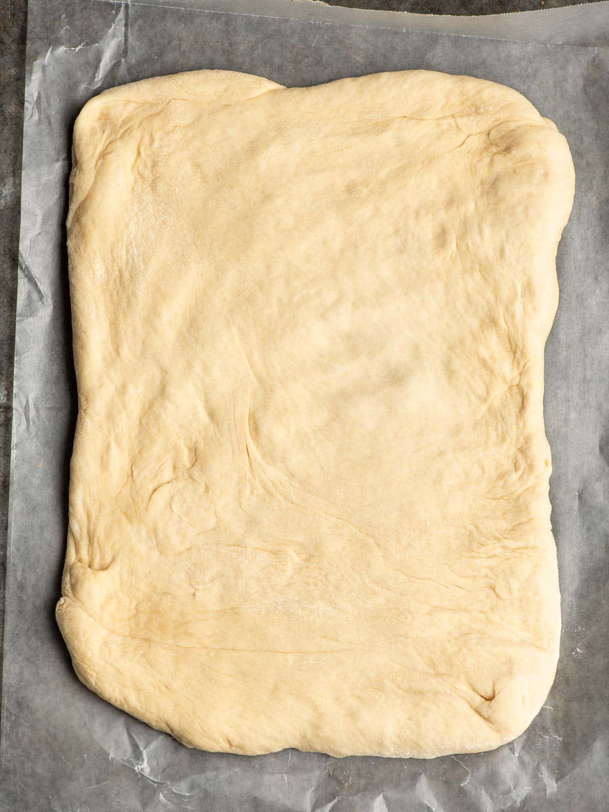 Bread dough pressed out into a rough 9 x 13 inch rectangle.