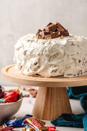 Candy Bar Layer Cake on a wooden cake stand.