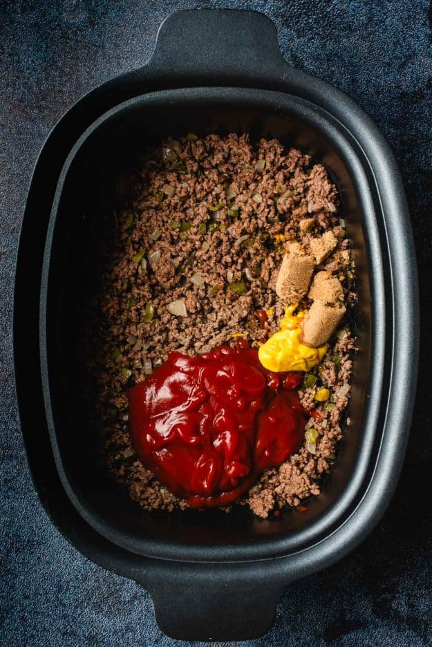 Slow cooker filled with ground beef, ketchup, mustard, brown sugar, worcestershire, and apple cider vinegar.