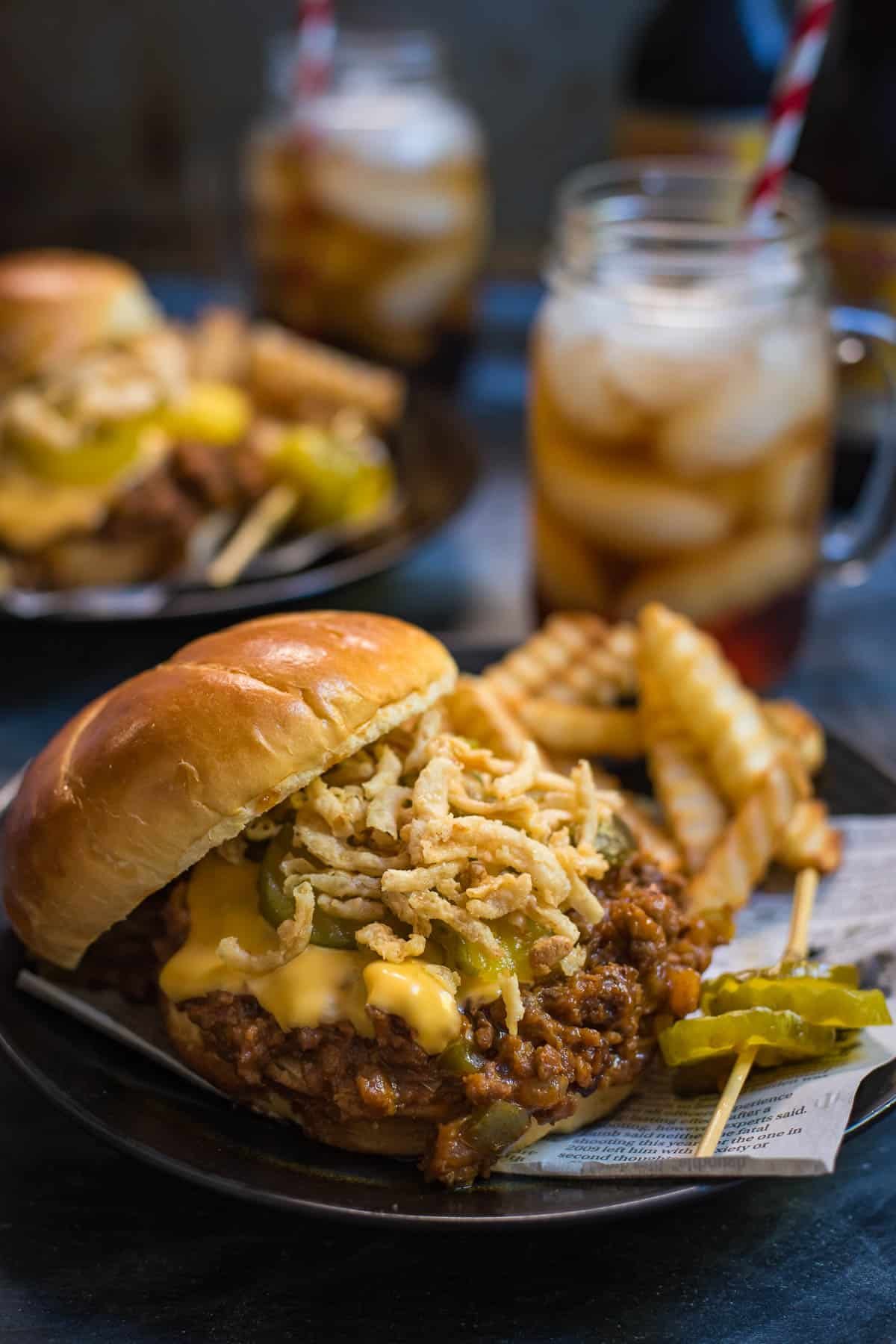 Slow Cooker Sloppy Joe Sandwich with melted cheese, french fried onions, and pickles.