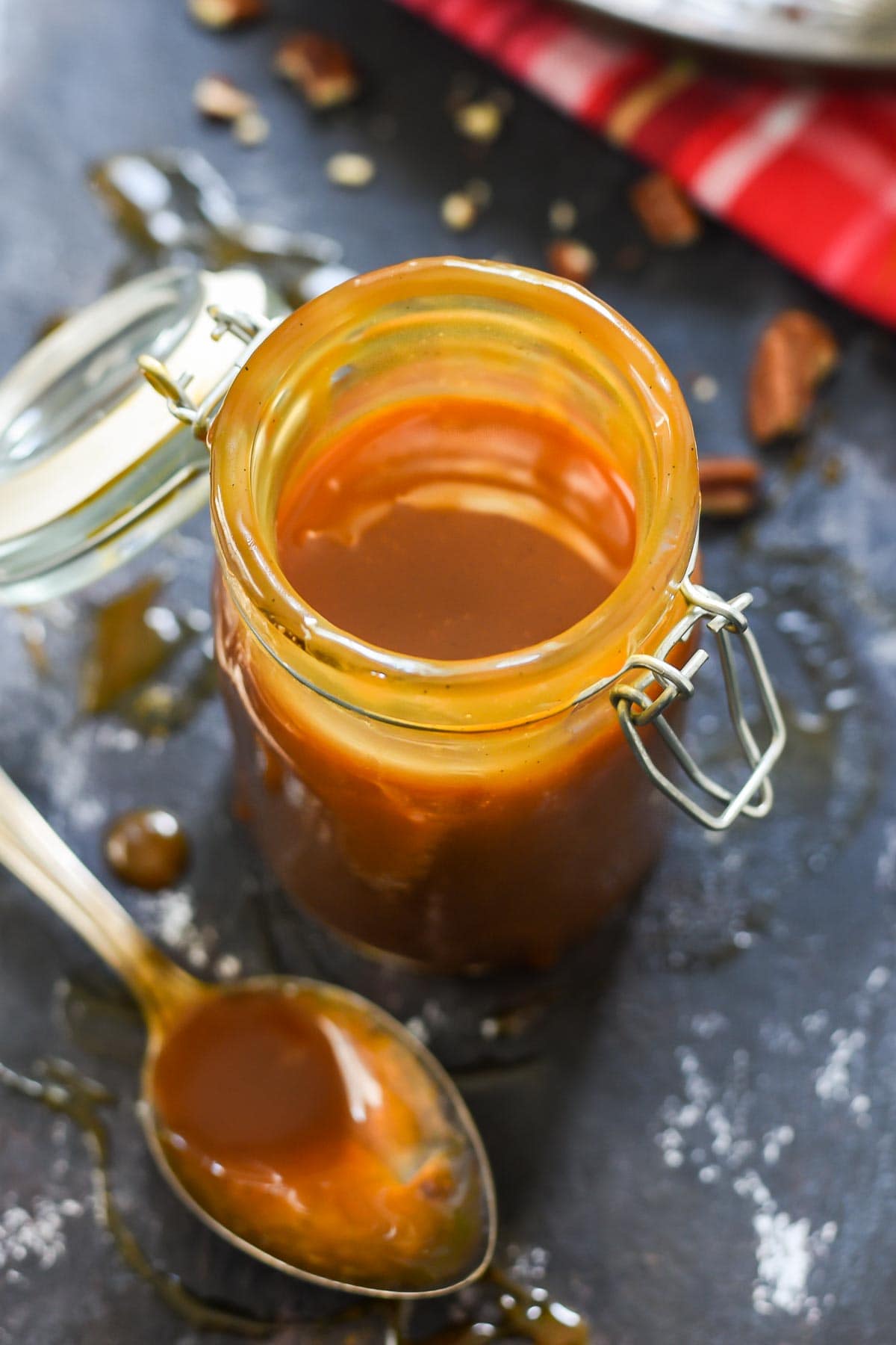 a jar of homemade caramel sauce with a spoon beside