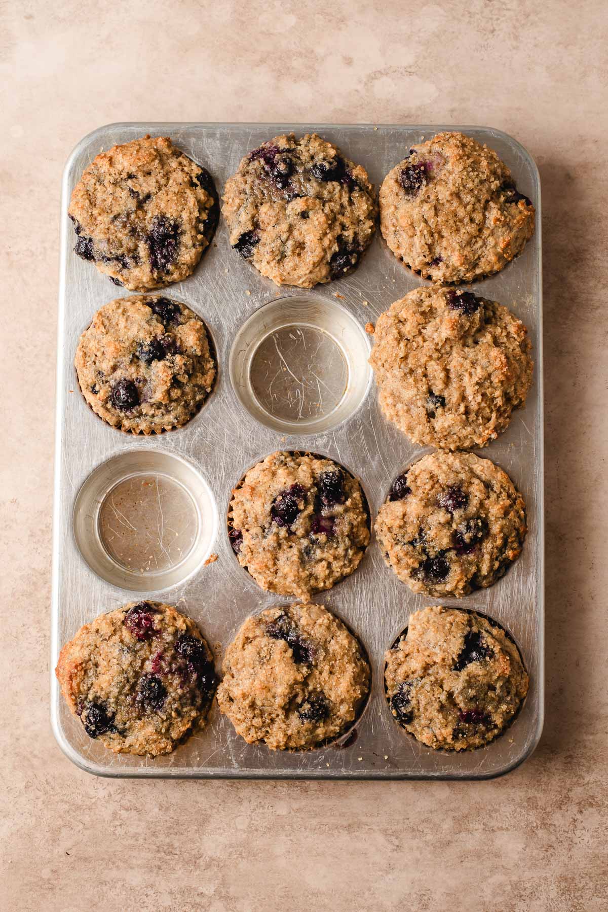 Freshly baked blueberry oat muffins in a muffin tin.