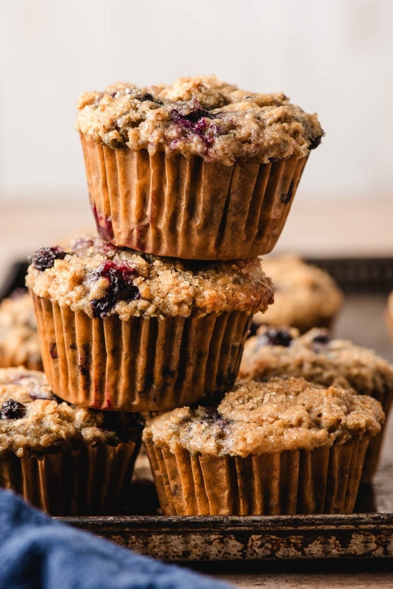 Blueberry oat muffins stacked on an old baking sheet.
