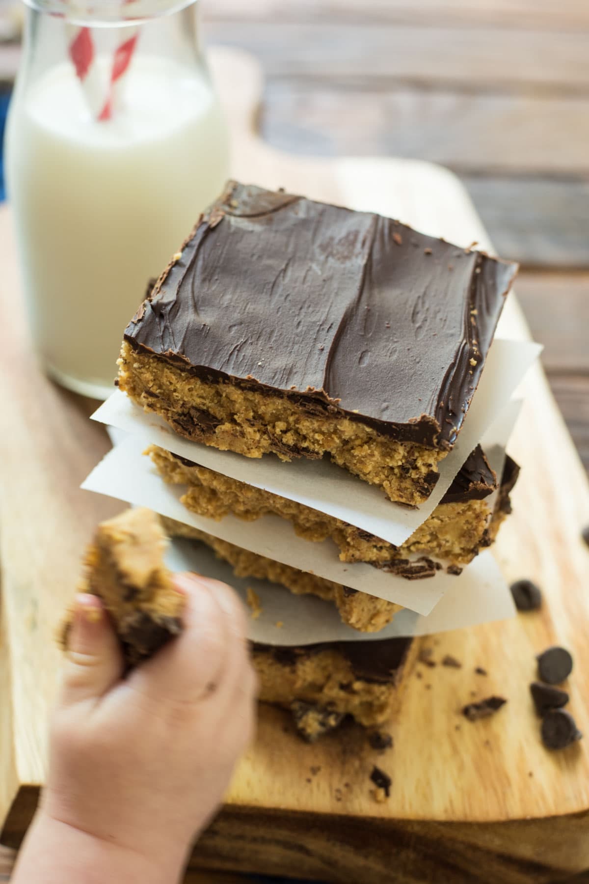 a hand takes a piece of a no bake peanut butter bar dessert from a stack