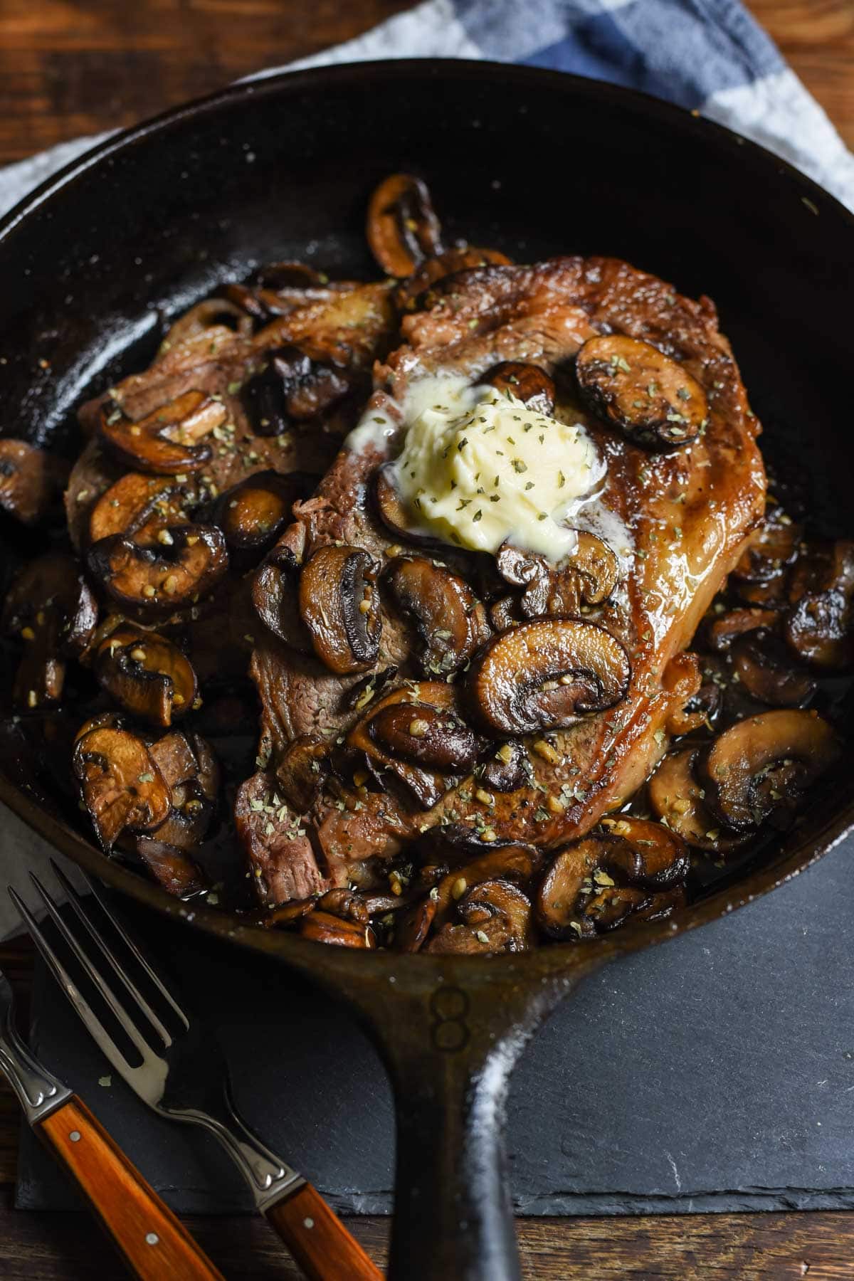 buttery garlic mushrooms smother a cast iron ribeye steak
