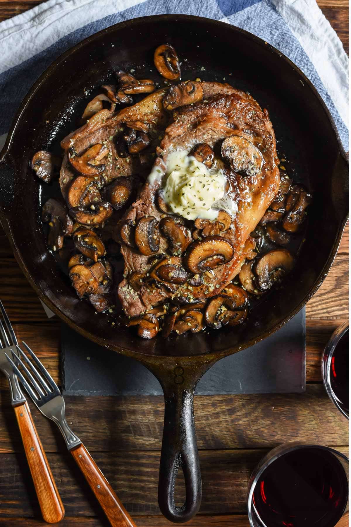 Cast Iron Ribeye Steak served in a skillet with garlic mushrooms and topped with butter