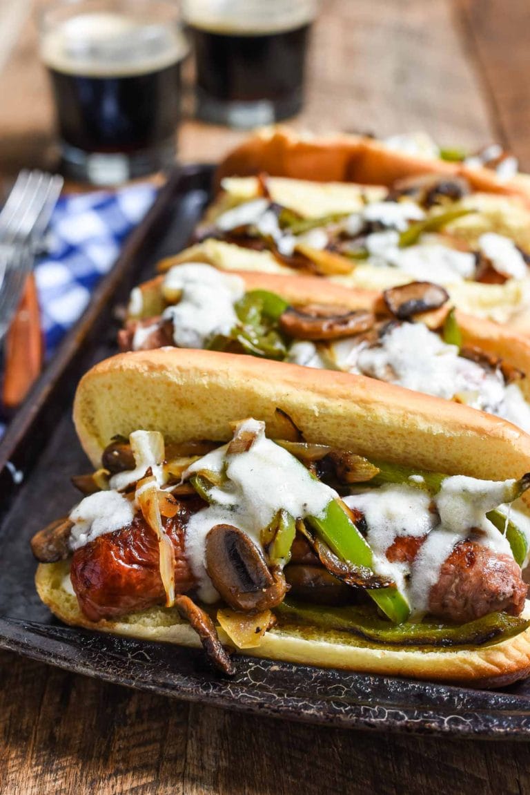 Philly Cheese Brats are a quick 30 minute meal perfect for grilling! Juicy brats with bell peppers, onions, mushrooms, and a creamy cheese sauce!