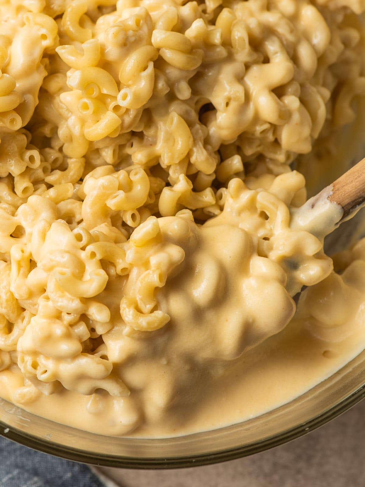 Bowl full of elbow macaroni being stirred into a creamy cheese sauce.