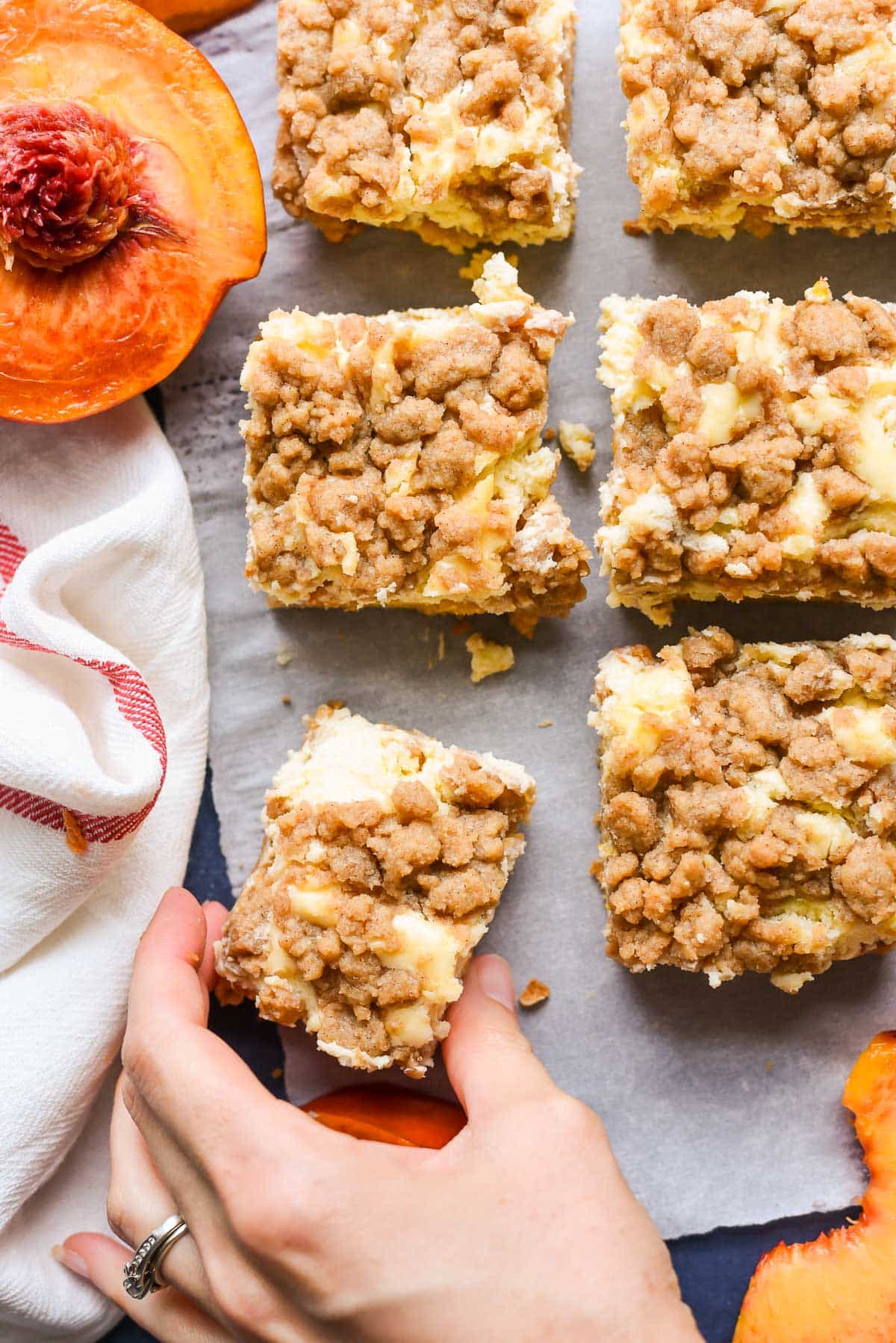 Hand taking a slice of peach cobbler cheesecake bar.