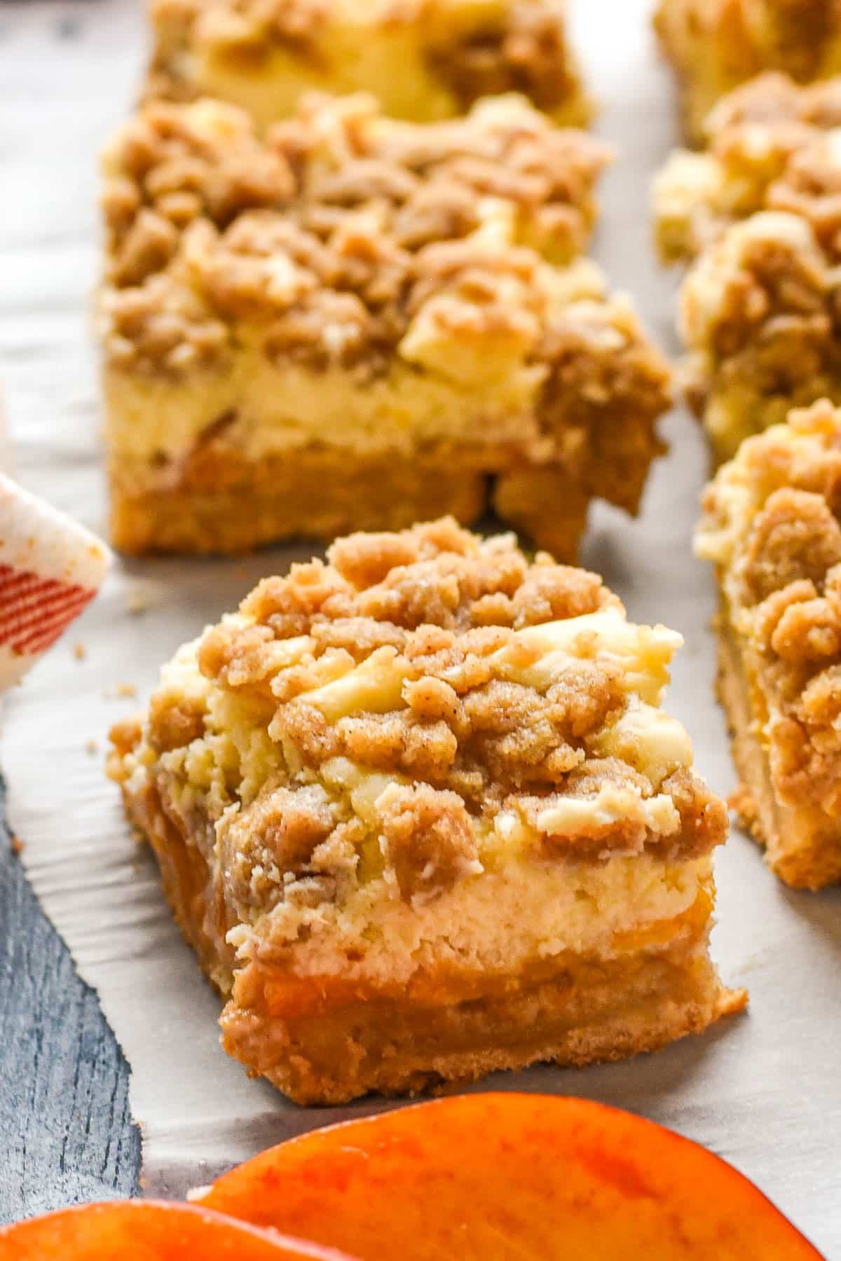 Slice of peach cheesecake bar with a crumb topping.
