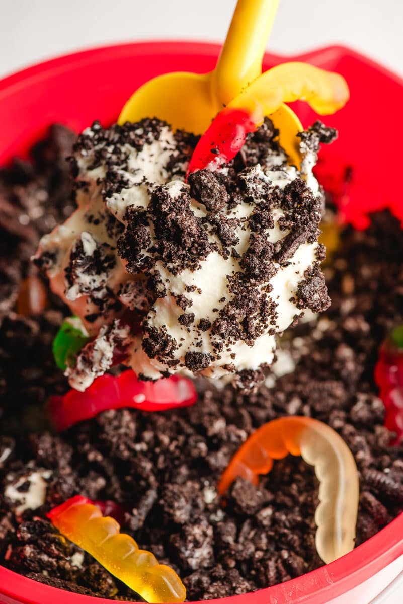 Sand shovel scooping up Oreo Dirt Cake with gummy worms.