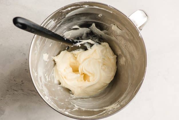 Cream cheese and powdered sugar beat together in the bowl of an electric mixer.