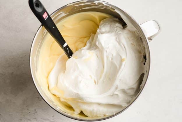 Whipped topping being stirred into vanilla pudding.