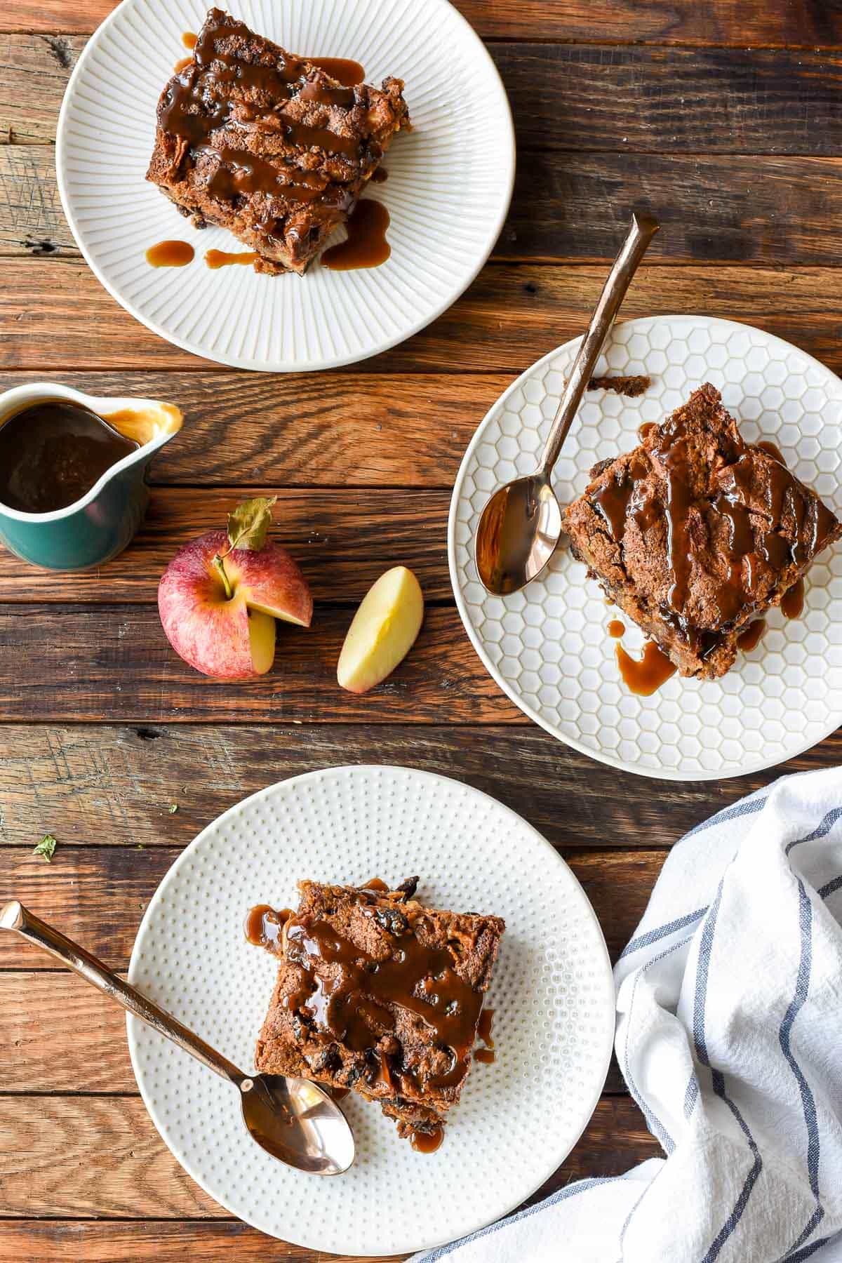 overhead picture of three slices of spiced apple cake with caramel sauce on a wooden table
