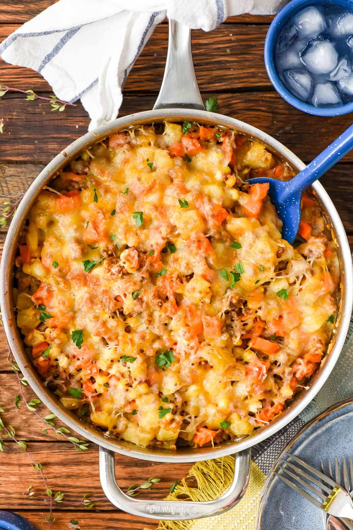 Large skillet of ground beef and vegetable saute with a spoon.