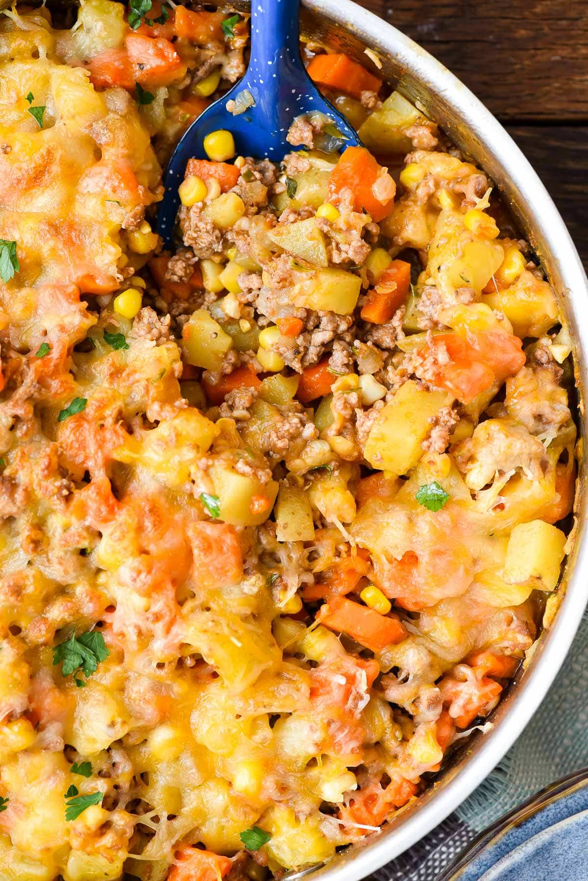 Spoonful of ground beef, potatoes, corn, and carrots with cheese on top.